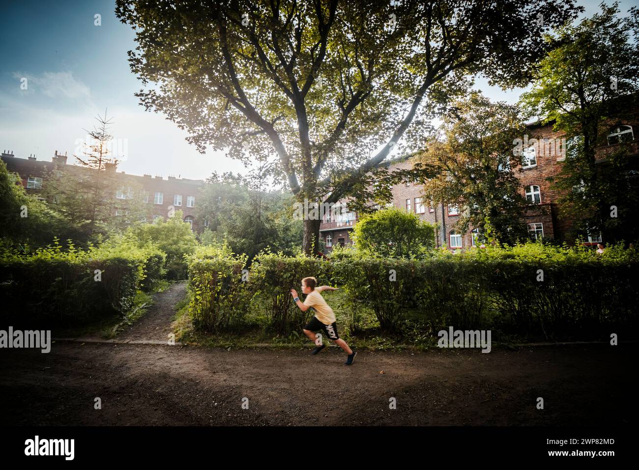 Nikiszowiec, Polonia - 14 aprile 2020: Un ragazzo che corre attraverso il cortile verde nel distretto minerario di Katowice, Slesia Foto Stock