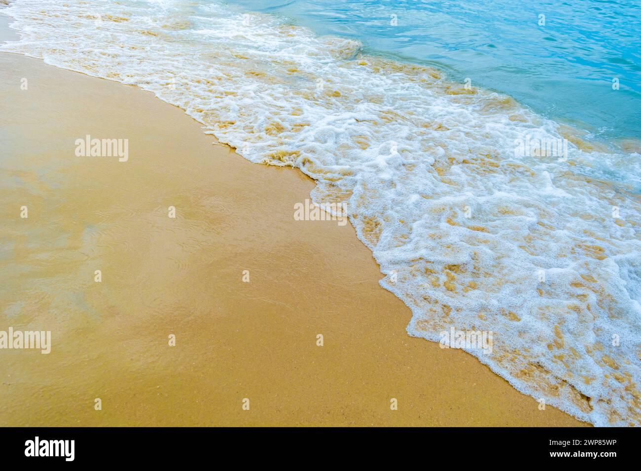 Una vista panoramica delle onde dell'oceano che si infrangono dolcemente su una spiaggia sabbiosa Foto Stock