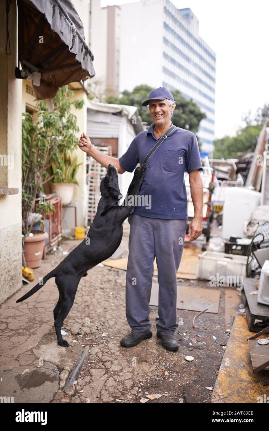 Uomo, cane e povera povertà nelle strade, nella classe inferiore e nella spazzatura o nell'economia sociale. Sorridi, uomo e animali domestici ammessi in vicoli con infrastrutture scadenti Foto Stock