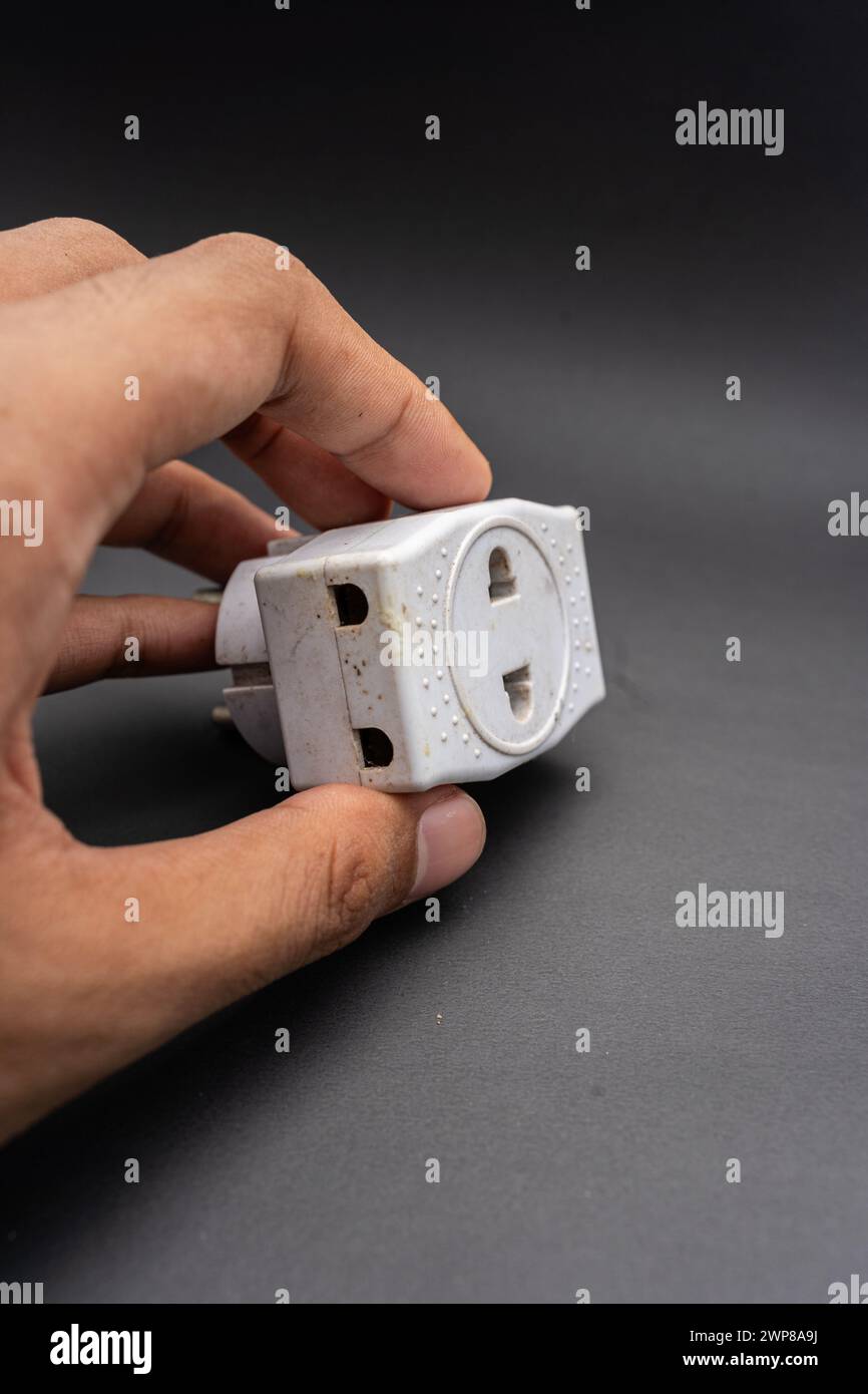 Rubinetto di uscita triplo usato sporco. Adattatore di energia elettrica utilizzato per dividere la presa utilizzata per i viaggi. Adattatore elettrico isolato su sfondo nero. Foto Stock