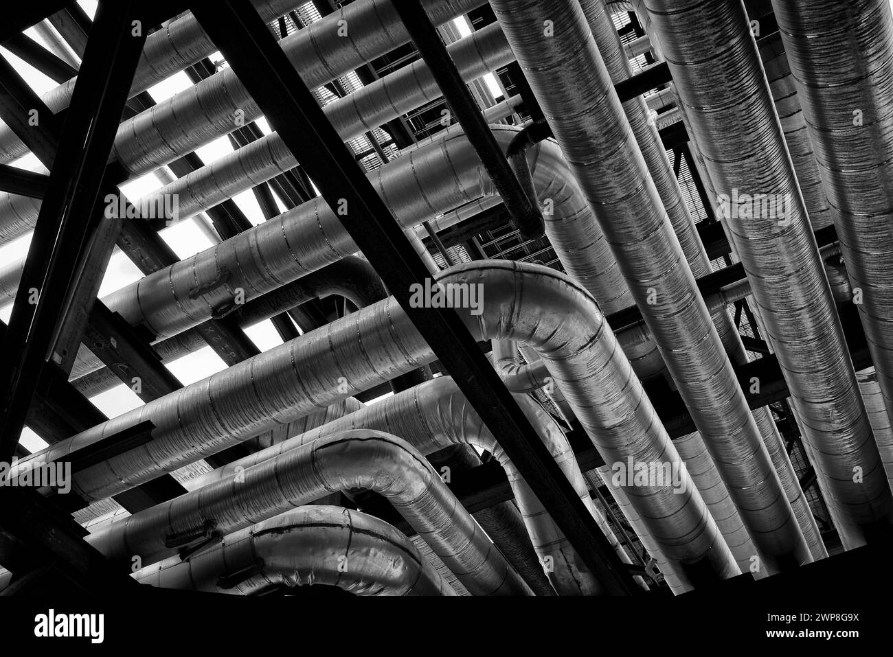 Una fotografia in bianco e nero di tubi lucidi in una raffineria di petrolio industriale Foto Stock