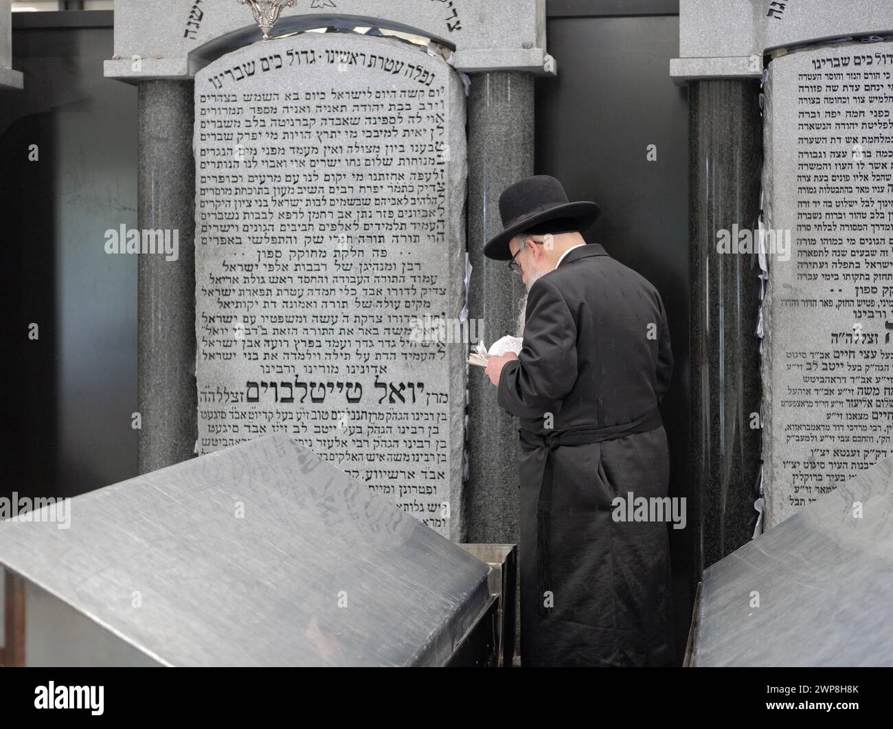 Un ebreo ortodosso prega accanto alla lapide di Rabbi Joel Teitelbaum, il primo Gran Rabbino Satmar. Presso l'Old Satmar Cemetery di Kiryas Joel, Foto Stock