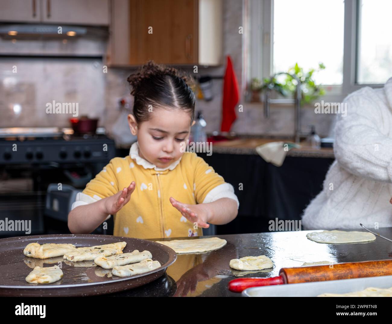 nipote che aiuta sua nonna a fare dolci in cucina, madre ama le emozioni Foto Stock