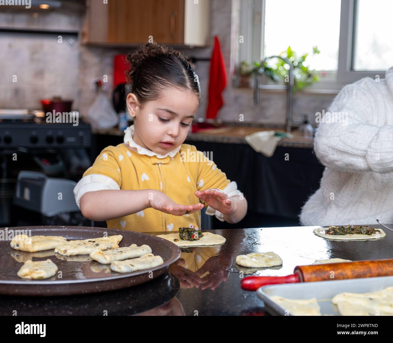 nipote che aiuta sua nonna a fare dolci in cucina, madre ama le emozioni Foto Stock