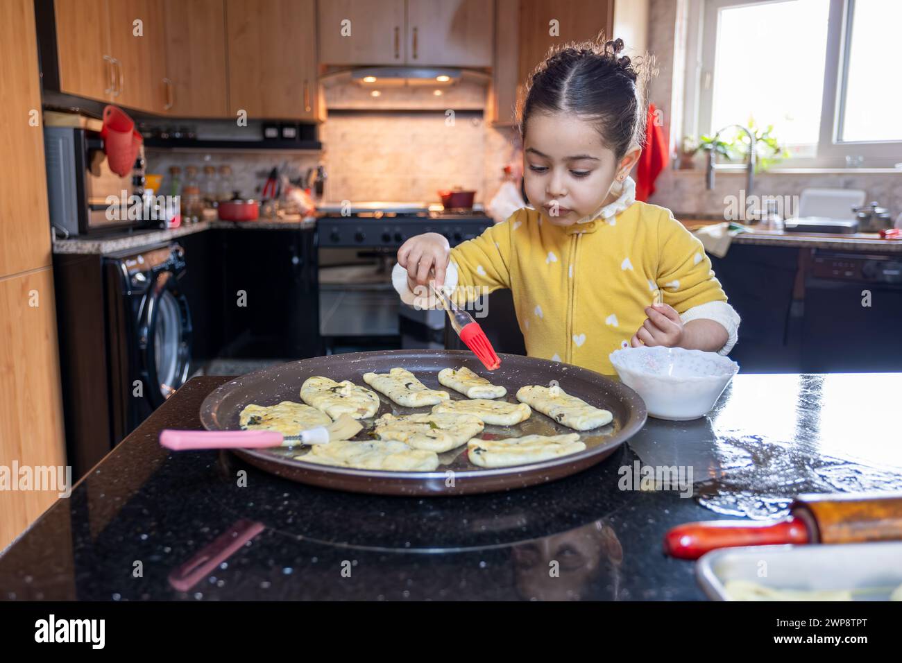 nipote che aiuta sua nonna a fare dolci in cucina, madre ama le emozioni Foto Stock