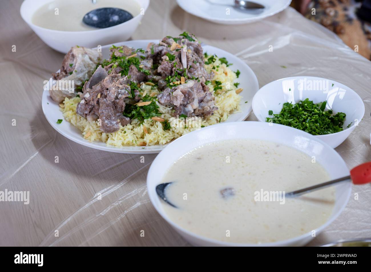 Il mansaf giordano sul tavolo della famiglia per la cena, pronto per essere consumato, sembra caldo e fresco con condimento di carne e mandorle Foto Stock