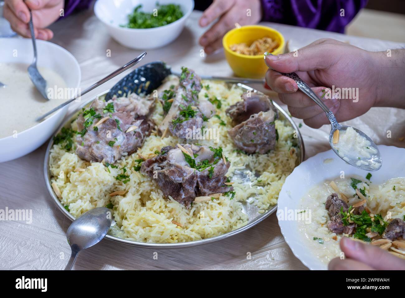 mani maschili con mansaf da un punto di vista mentre preparava il suo piatto con carne, riso ricoperto in camicia, noci e prezzemolo durante l'iftar nel ramadan Foto Stock