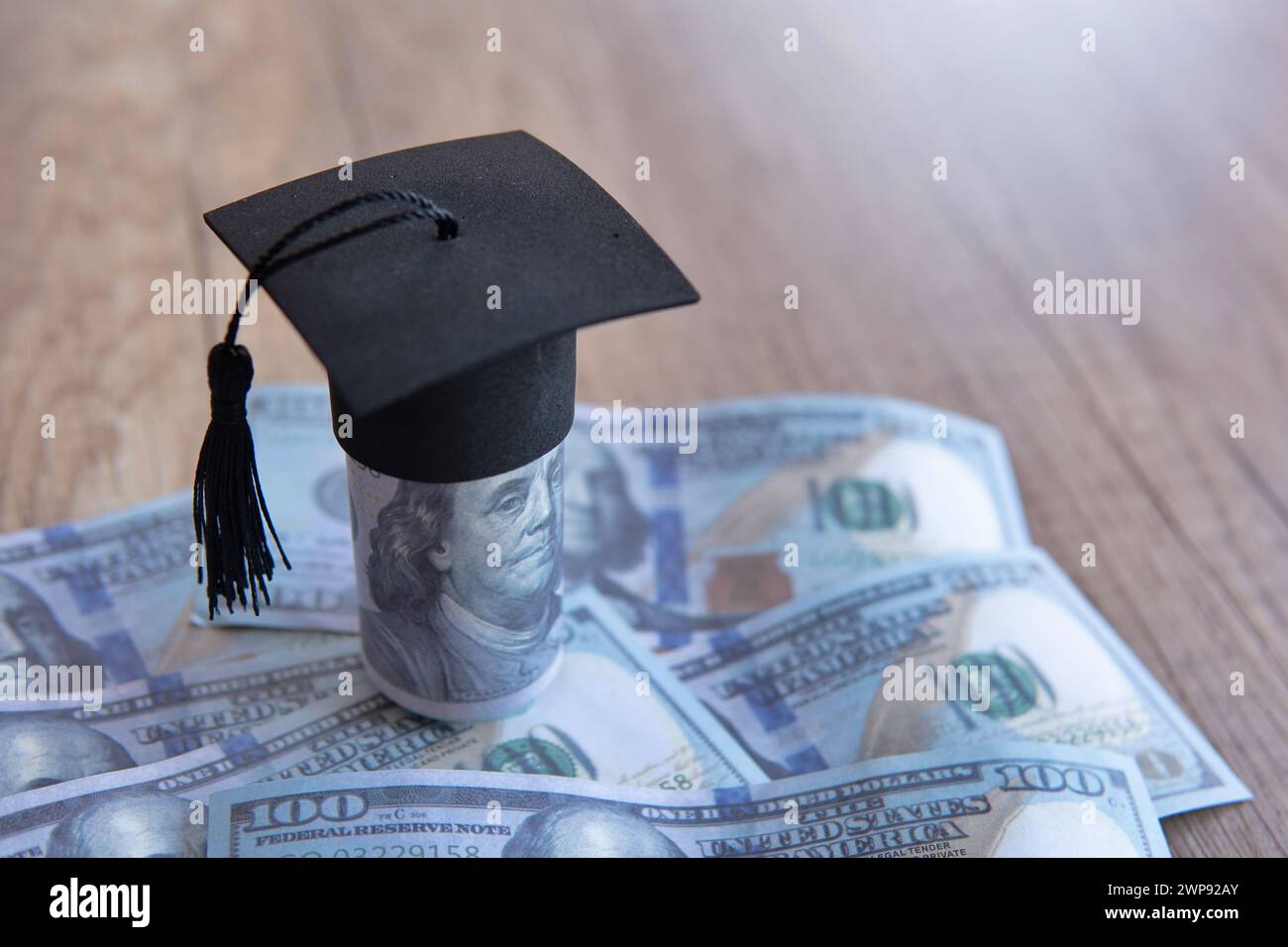 Immagine ravvicinata del cappello di graduazione e dei soldi sul tavolo. Borsa di studio, concetto di tasse educative. Copia spazio per il testo. Foto Stock
