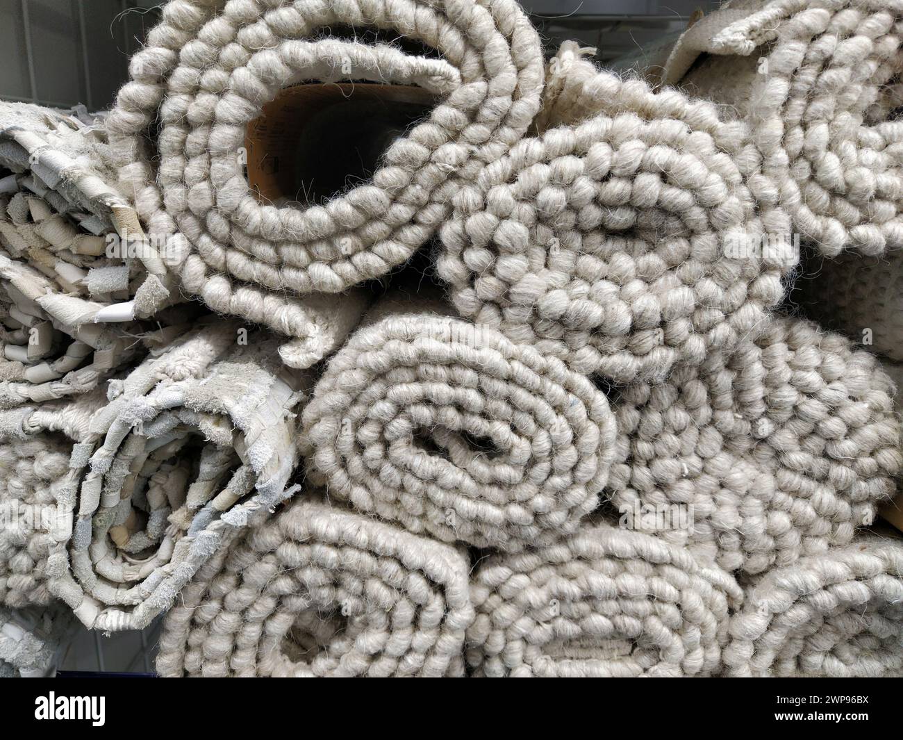 Morbidi tappeti bianchi e grigi piegati in matasse, rotoli e fasci. Un assortimento di copriletto su uno scaffale del negozio. Le coperte sono splendidamente posate Foto Stock