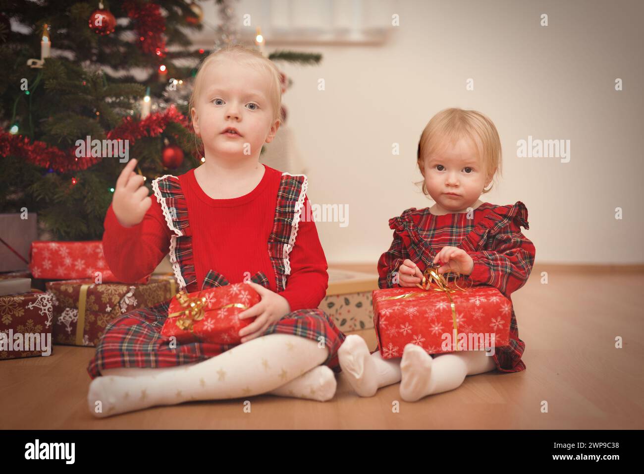 Bambini al momento del giorno di natale che disimballano i regali vicino all'albero Foto Stock