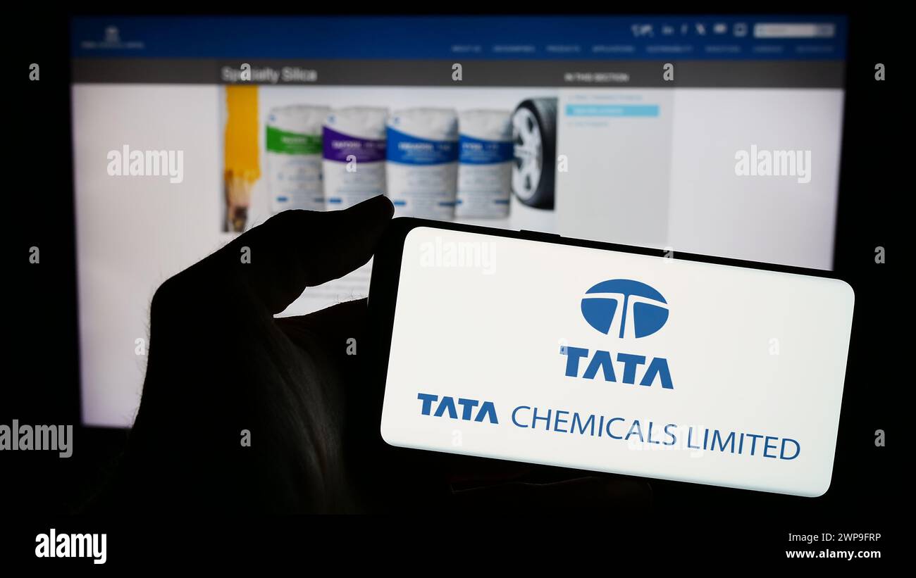 Persona che detiene un telefono cellulare con il logo della società chimica indiana Tata Chemicals Limited di fronte alla pagina web aziendale. Mettere a fuoco il display del telefono. Foto Stock