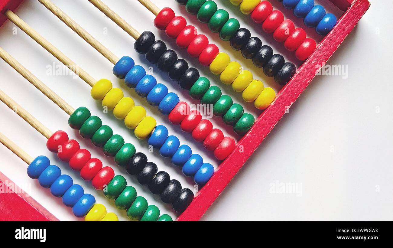 Abaco di legno. Telaio in legno rosso con aste trasversali. Elementi in legno rosso, blu, giallo, verde, nero. Strumento matematico su sfondo bianco. Primo piano. Copia Foto Stock