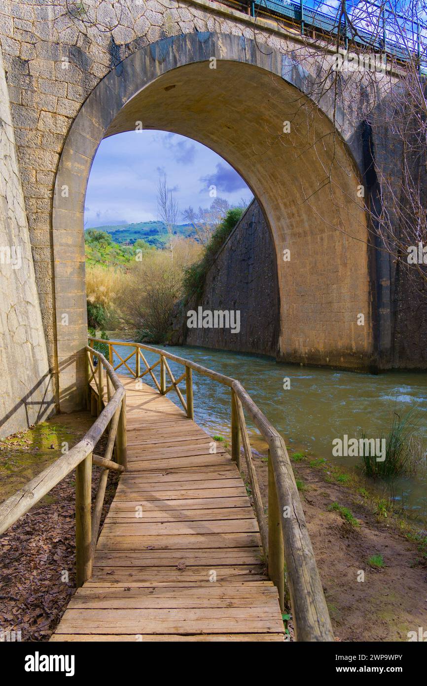 passerella in legno su un fiume di montagna con un tunnel di pietra sullo sfondo Foto Stock