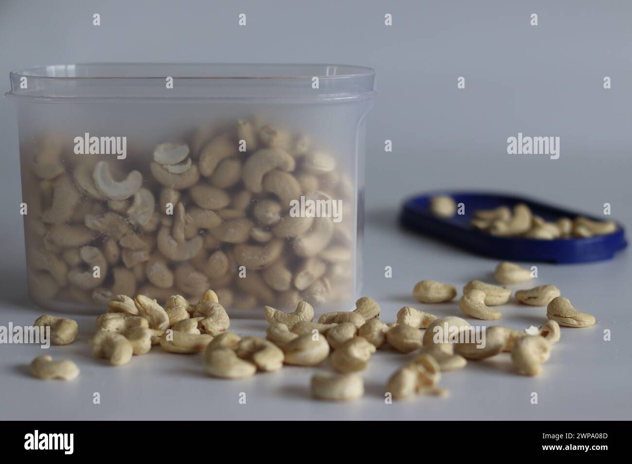 Un mucchio di anacardi arrostiti dorati in un contenitore di plastica. Perfetto per spuntini e delizie culinarie, catturando l'essenza della qualità e dell'irresi Foto Stock