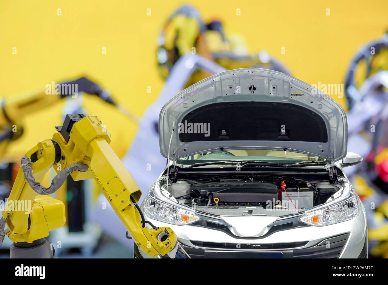 Robotica industriale che lavora con l'automobile su un background sfocato di fabbrica di auto intelligenti, lavoro robotico al posto di umano, industria 4,0 e concetto di intelligenza artificiale Foto Stock