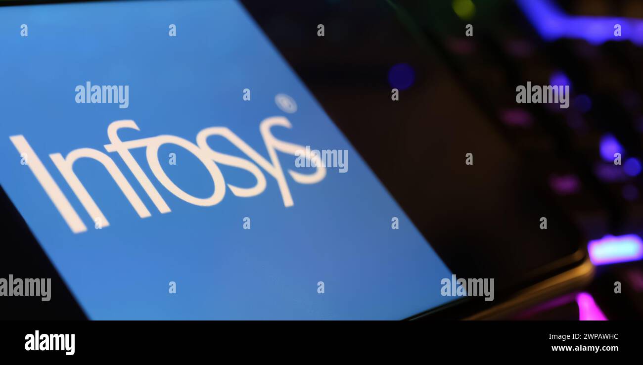 Viersen, Germania - 1 marzo. 2024: Primo piano dello schermo dello smartphone con logo di Infosys sulla tastiera del computer Foto Stock