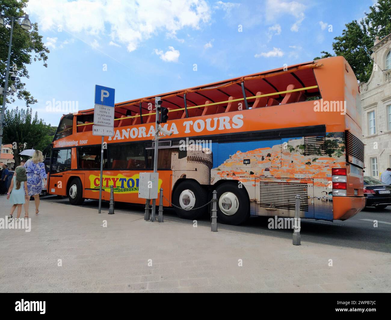 Dubrovnik, Croazia, 18 agosto 2022. Autobus turistico arancione a due piani alla fermata dell'autobus. La donna e la ragazza hanno fretta. Strada e. Foto Stock