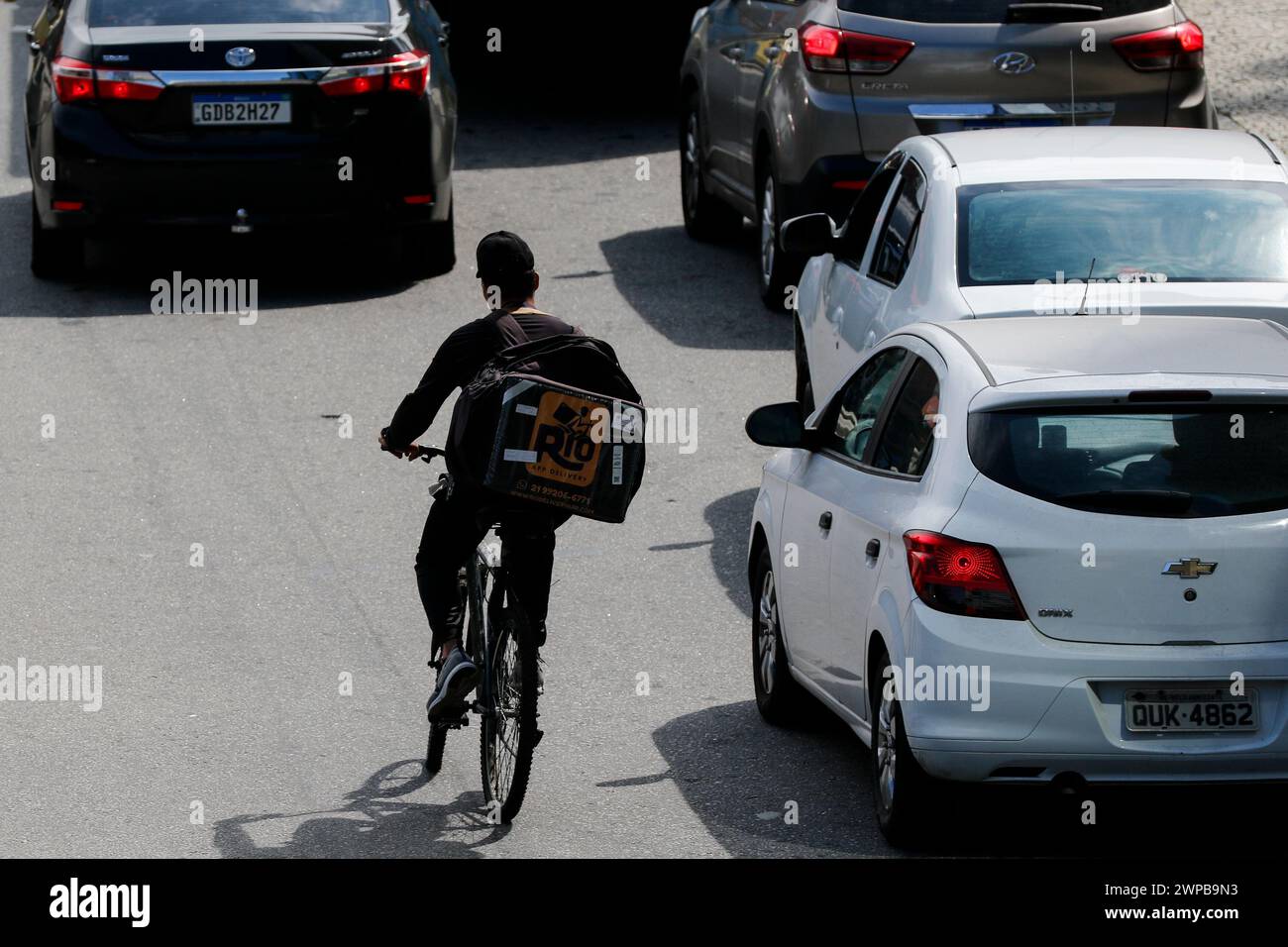 Addetto alle consegne. Consegna di alimenti tramite il servizio di applicazioni per telefoni cellulari. Borsa da trasporto per ciclisti Deliveryman. Lavoro dell'app logistica Foto Stock