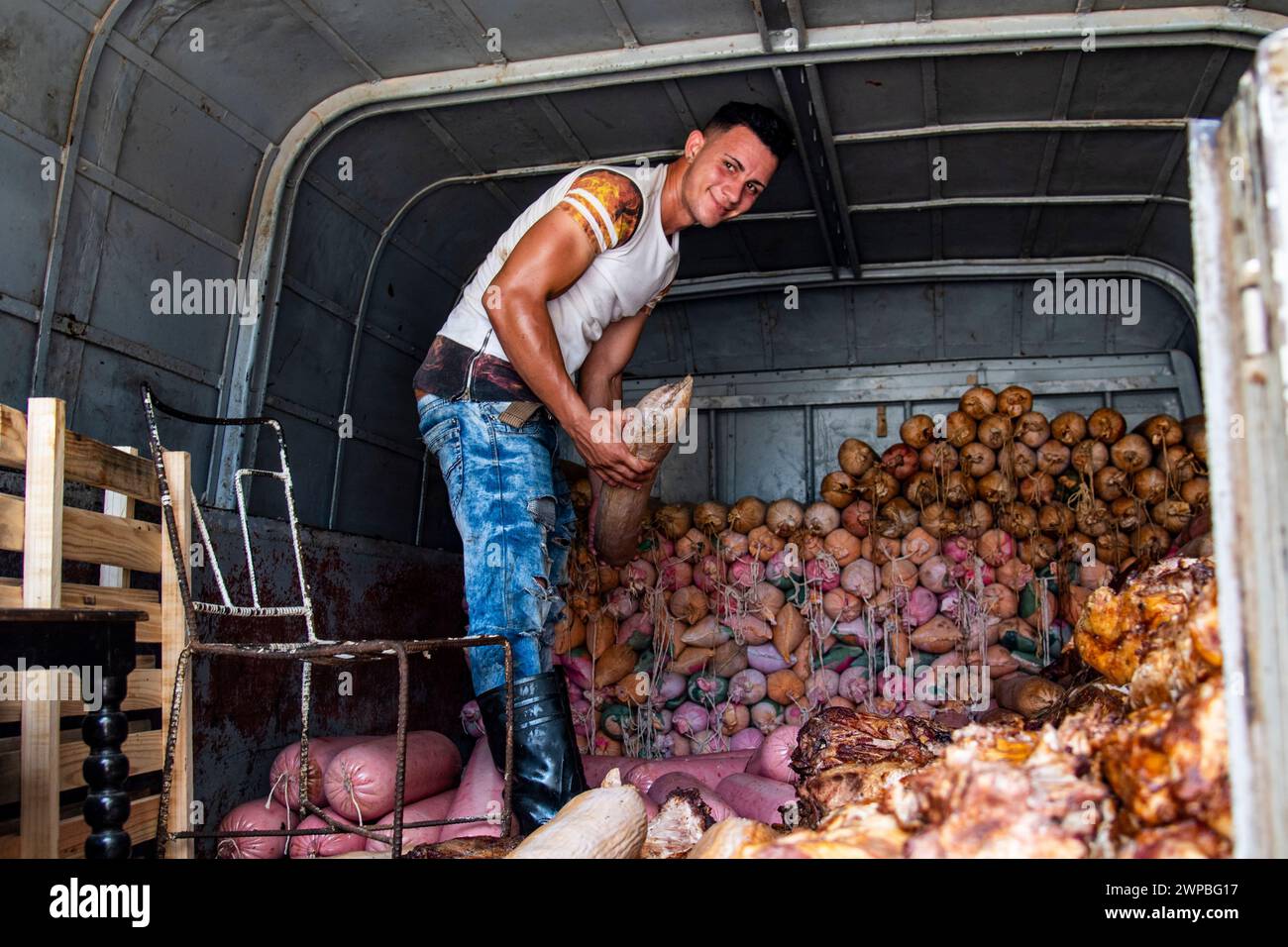 Un giovane che suda e trasuda in una giornata calda, lavora a lanciare e consegnare cibo in un bar a l'Avana, Cuba Foto Stock