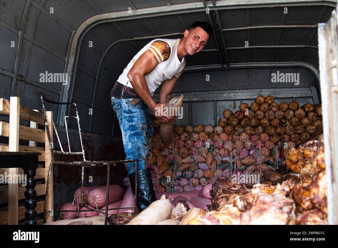 Un giovane che suda e trasuda in una giornata calda, lavora a lanciare e consegnare cibo in un bar a l'Avana, Cuba Foto Stock
