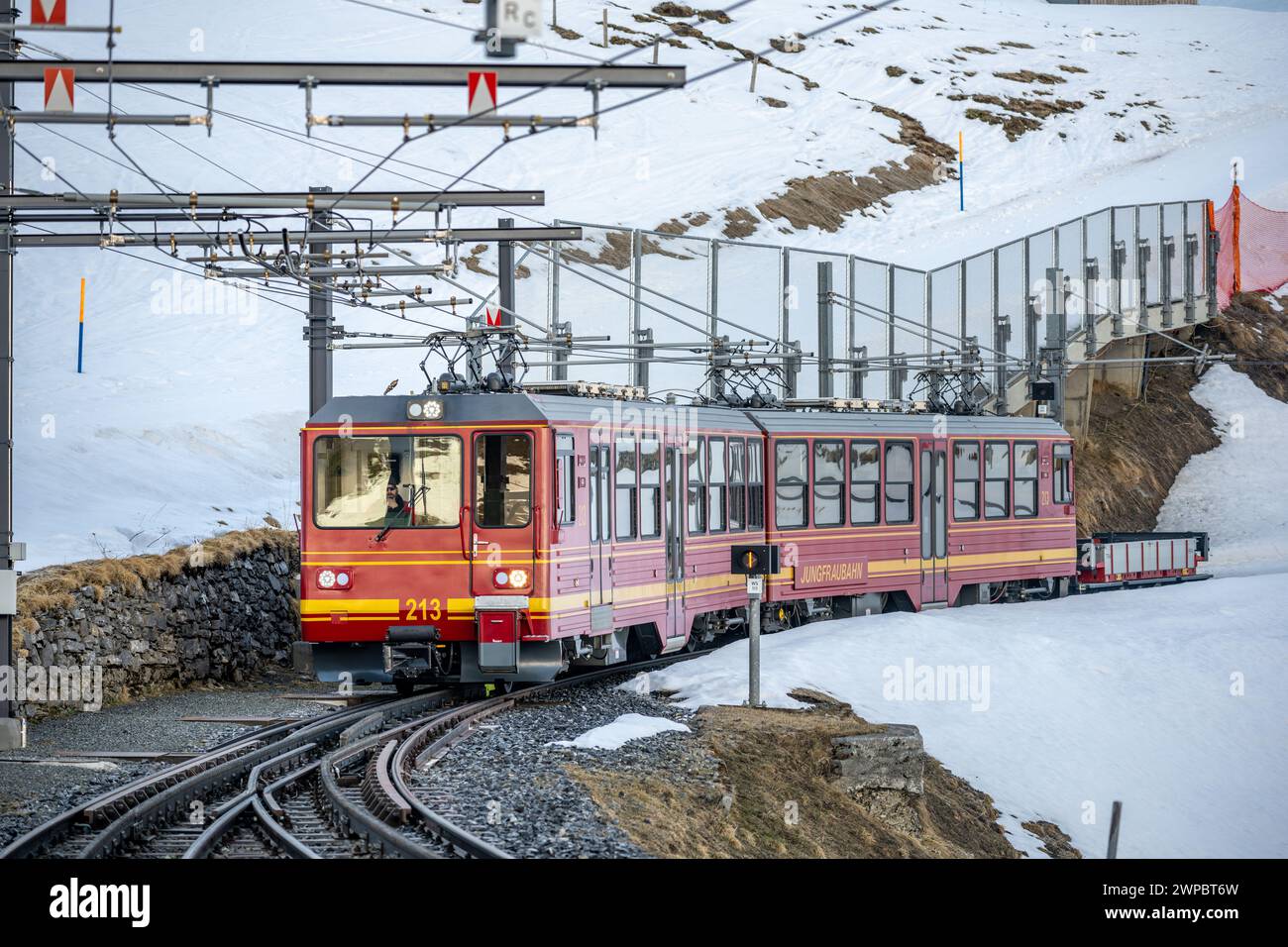 Un treno a cremagliera viaggia sulla ferrovia da Jungfraujoch (in cima all'Europa) a Kleine Scheidegg sulla collina innevata con Eiger, Monch e Jungfrau in Foto Stock