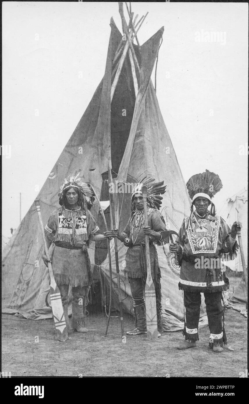 Fotografia storica d'epoca. "Un trio di indiani della tribù Caughnawaga con pagaie archi e frecce decorate" [tre Kahnawá:ke Mohawk uomini fotografarono indossando regalia, copricapi e posando con pagaie, archi e frecce di fronte a un tipo] Canada. 1914 Foto Stock