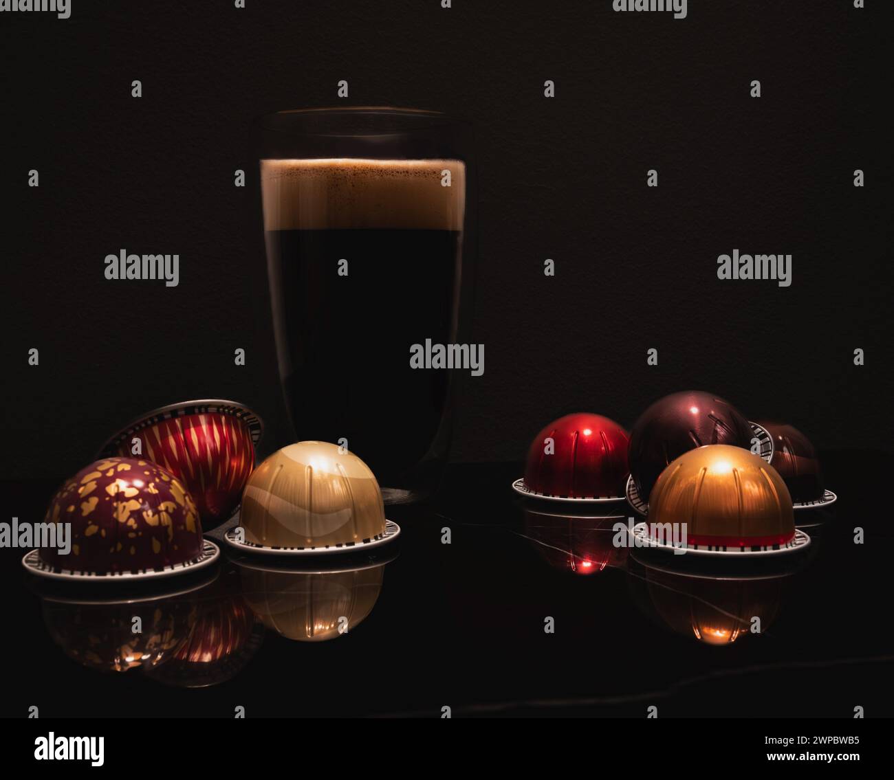 Caffè nero grande in una tazza di vetro a doppia parete con cialde colorate in schiuma Foto Stock