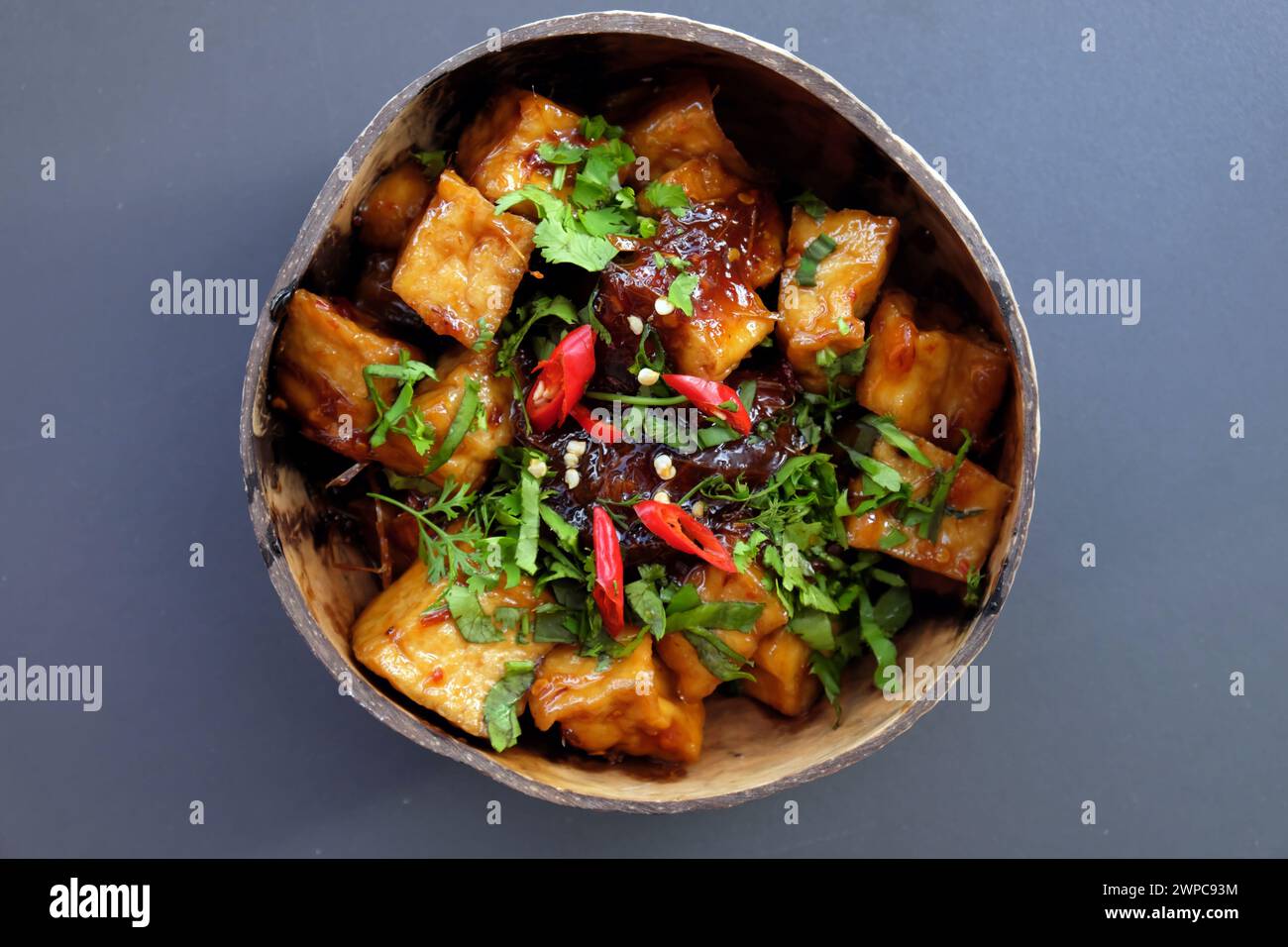 Vista dall'alto della ciotola di piatto vegano fatto in casa per vegetariani, tofu cucinato con pasta di tamarindo su sfondo grigio Foto Stock