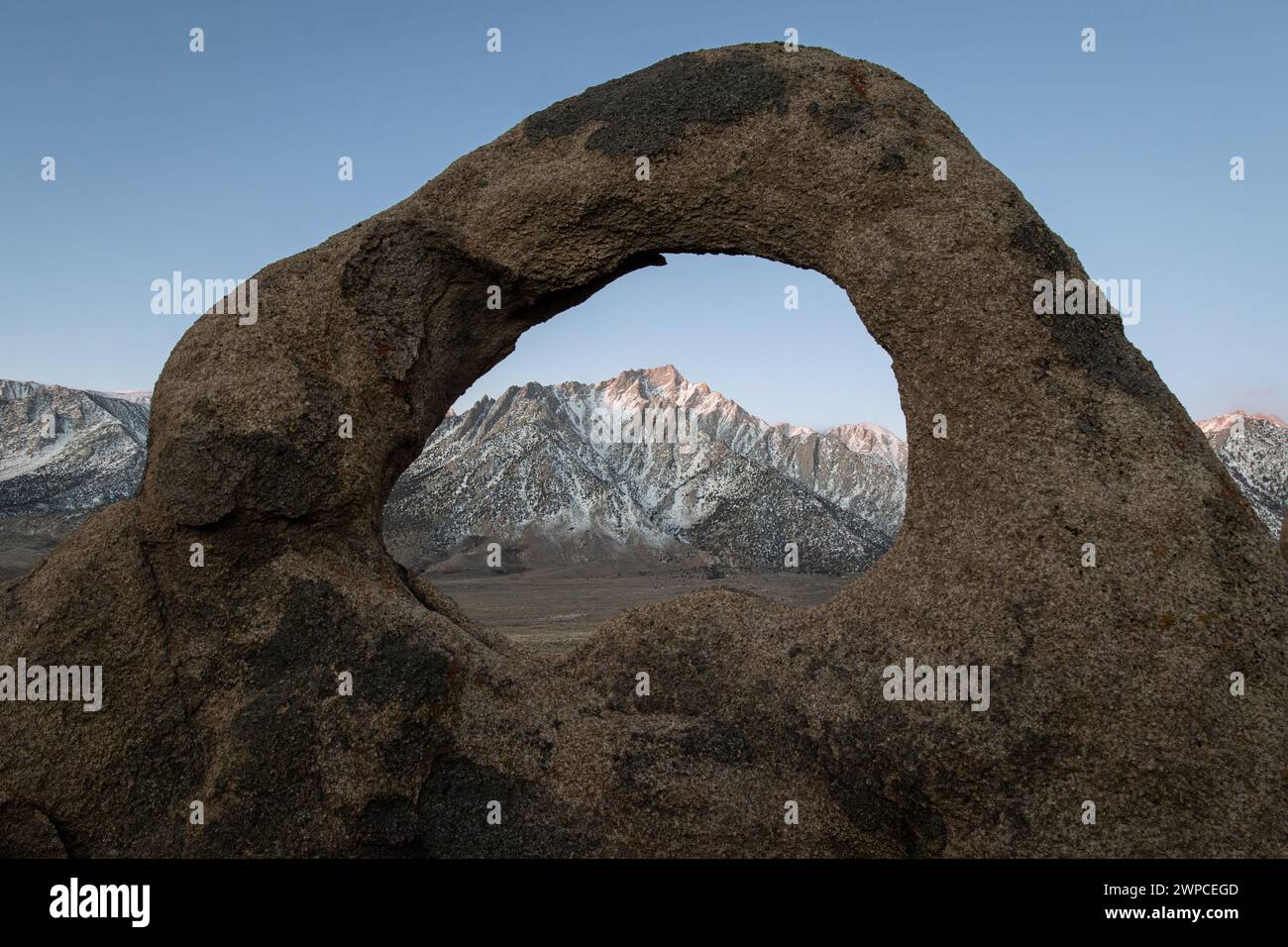 Whitney Arch, una formazione rocciosa ad arco naturale in pietra, incornicia il Monte Whitney e la catena montuosa della Sierra Nevada nel paesaggio delle Alabama Hills della California. Foto Stock