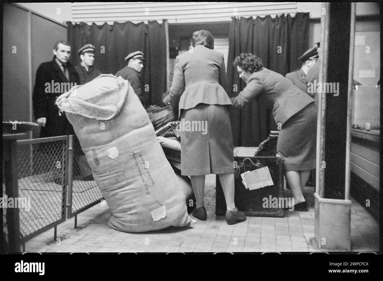 Fotografia dei doganieri che effettuano l'autorizzazione al passaporto e ai bagagli presso la stazione degli Esteri dell'aeroporto di Varsavia nel 1959, parte del "Please Open!" (si prega di aprire!) serie di fotogiornalismo. Foto Stock