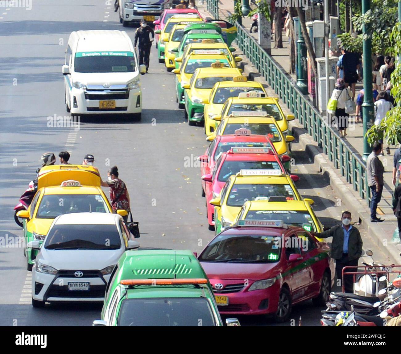 Una lunga fila di colorati taxi thailandesi che aspettano fuori dal mercato di Chatuchak a Bangkok, Thailandia. Foto Stock