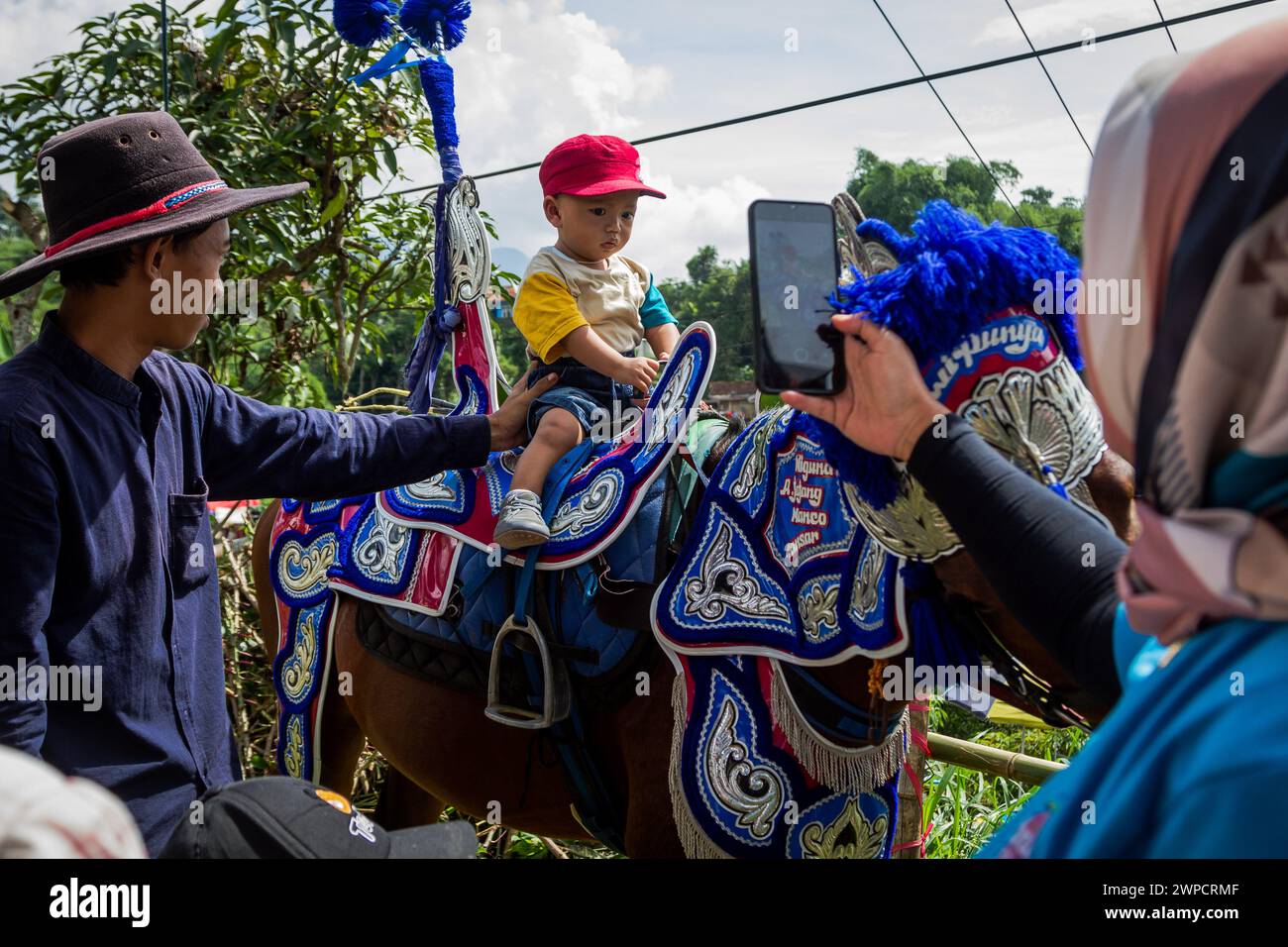 Sumedang, Giava occidentale, Indonesia. 7 marzo 2024. Una donna scatta una foto al suo bambino mentre cavalca un cavallo danzante prima di esibirsi a Tanjungsari, nella Reggenza di Sumedang. Dancing Horse, noto anche come ''Kuda Renggong'', è una delle arti dello spettacolo tradizionali e culturali di Sumedang La parola ''renggong'' deriva dal Sundanese ''ronggeng'' o ''kamonesan'' che significa abilità. Il cavallo renggong è stato addestrato nelle sue capacità per essere in grado di ballare secondo l'accompagnamento della musica tradizionale sundanese. (Credit Image: © Algi February Sugita/ZUMA Press Wire) SOLO PER USO EDITORIALE! Non per USO commerciale! Foto Stock