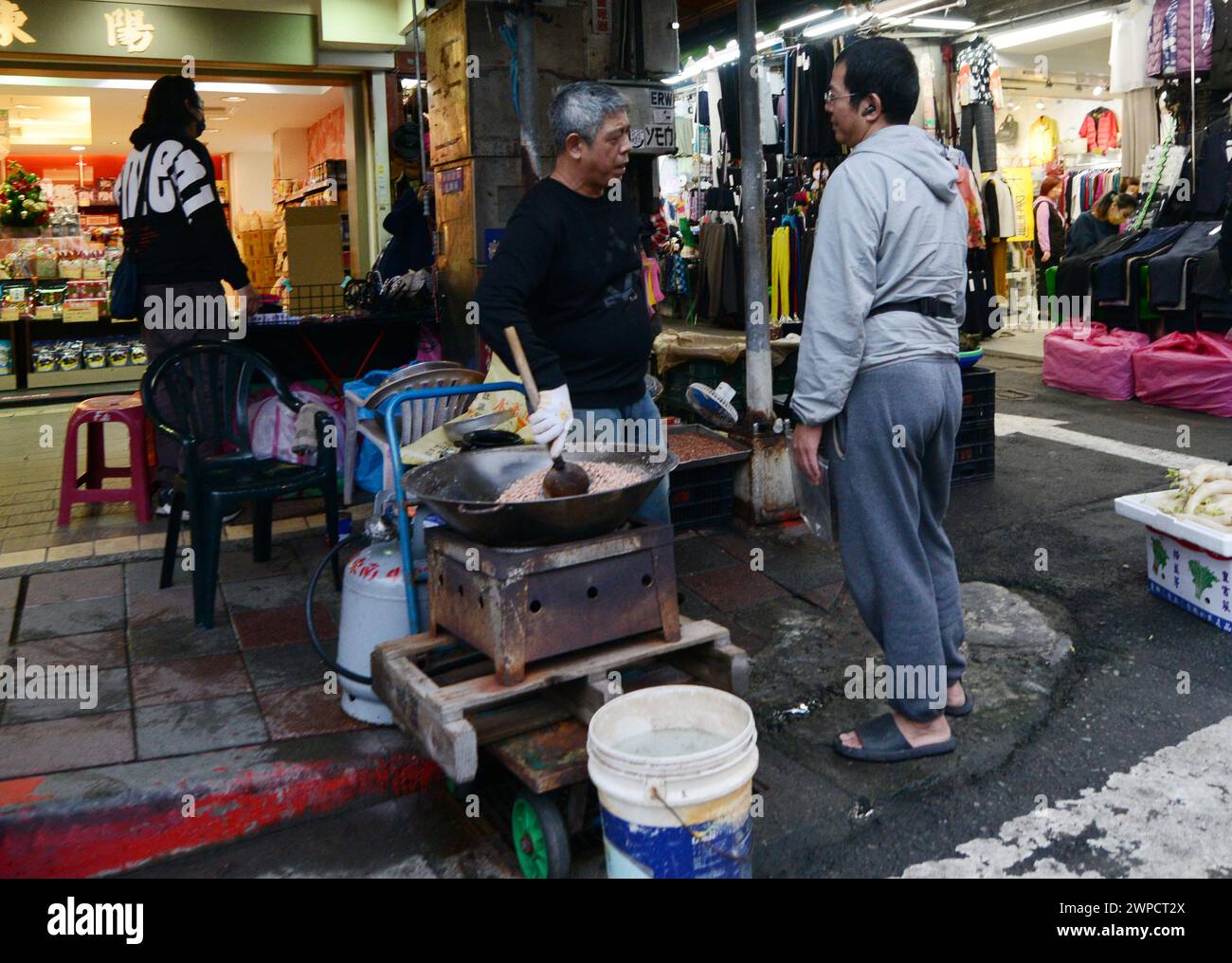 Un uomo che tosta arachidi su Dihua Street a Taipei, Taiwan. Foto Stock