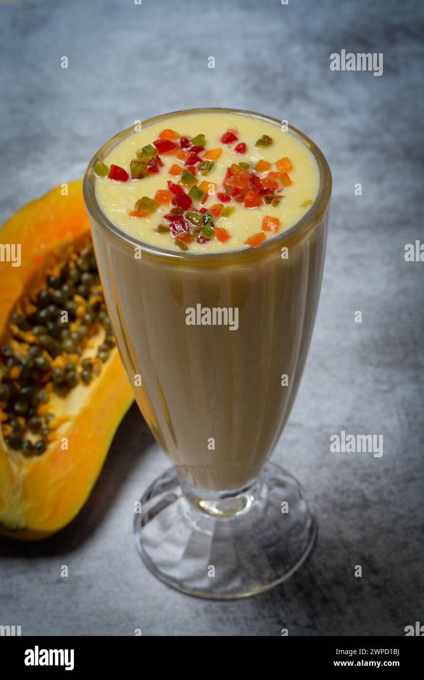 Un milkshake e mezzo di papaya matura su un tavolo. Foto Stock
