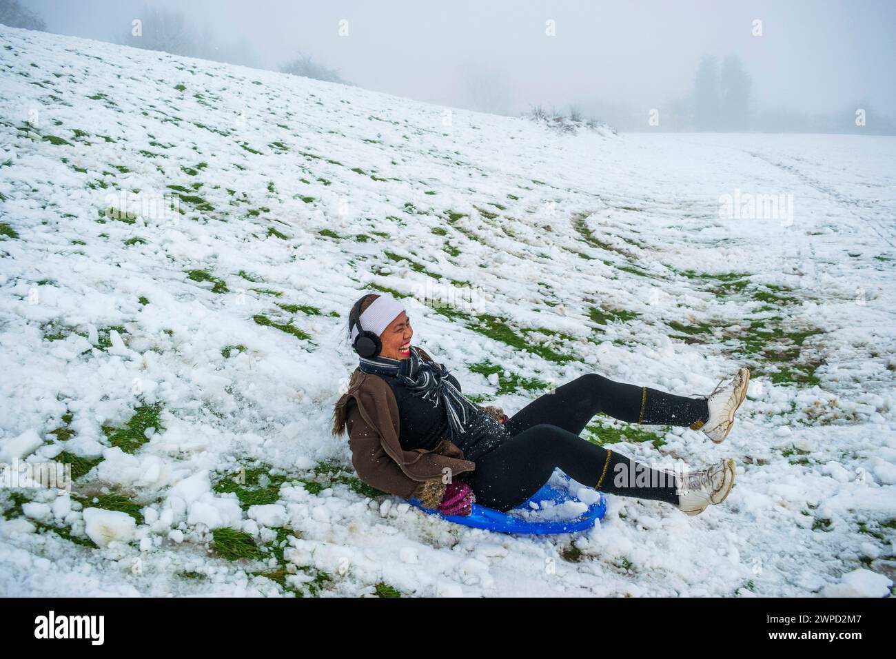 Una femmina filippina che ha divertimento in slitta per la prima volta nel Regno Unito neve, slittino, South Yorkshire, Inghilterra Foto Stock