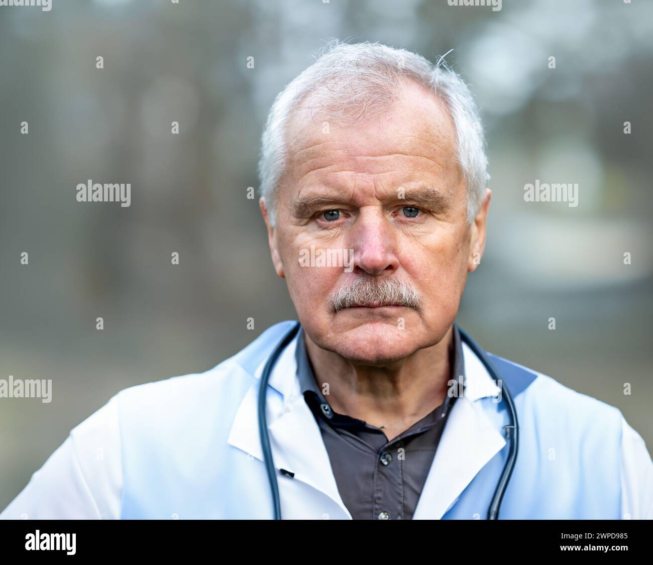 Ritratto di un medico anziano che guarda seriamente nella fotocamera. Foto Stock