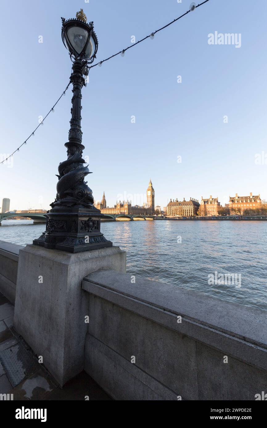 Regno Unito, Londra, lampada ornata lungo la Queen's Walk con il Palazzo di Westminster in lontananza. Foto Stock