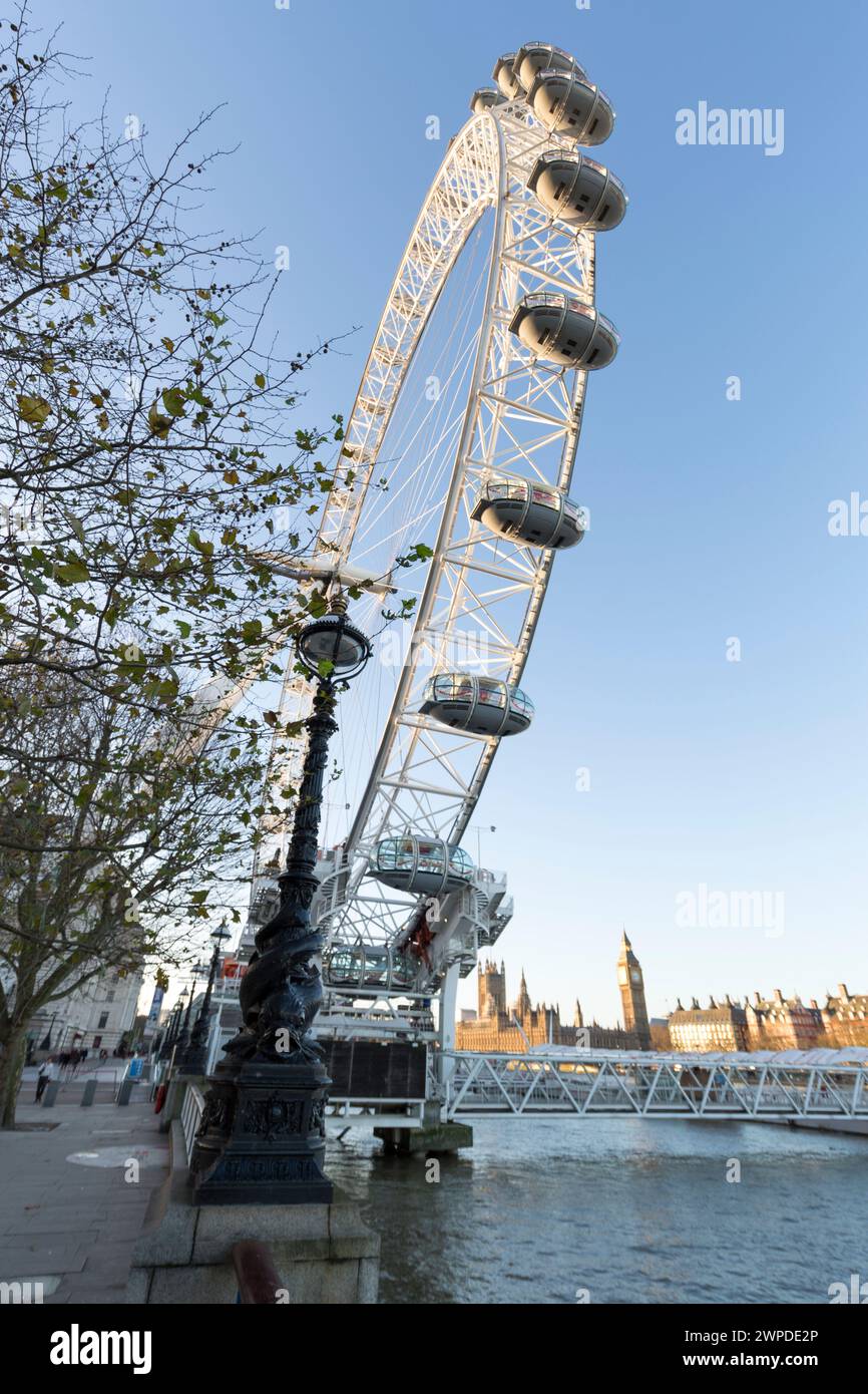Regno Unito, Londra, lampada ornata lungo la Queen's Walk con il London Eye e il Palazzo di Westminster in lontananza. Foto Stock