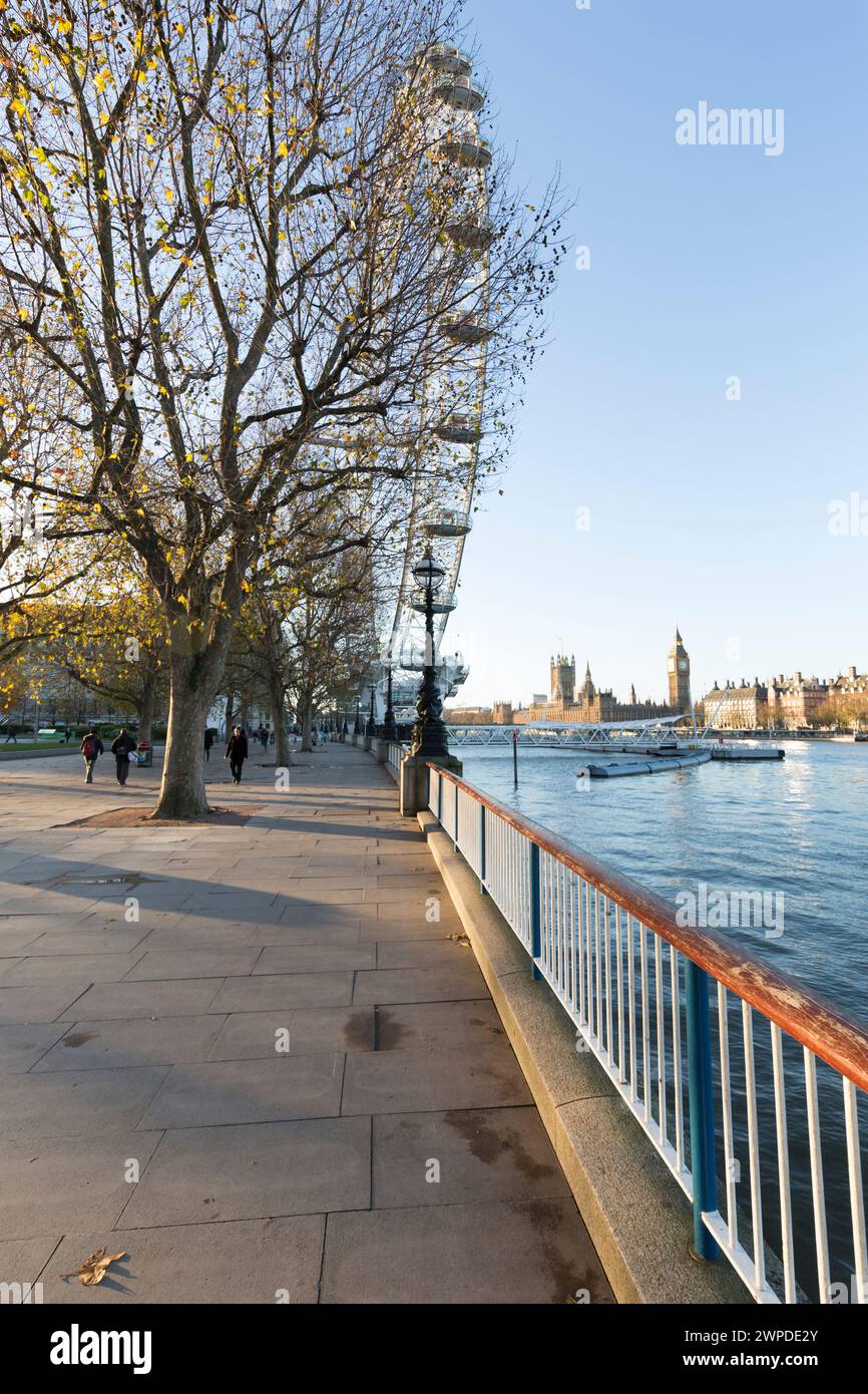 Regno Unito, Londra, vista lungo la Queen's Walk con il London Eye e il Palazzo di Westminster in lontananza. Foto Stock