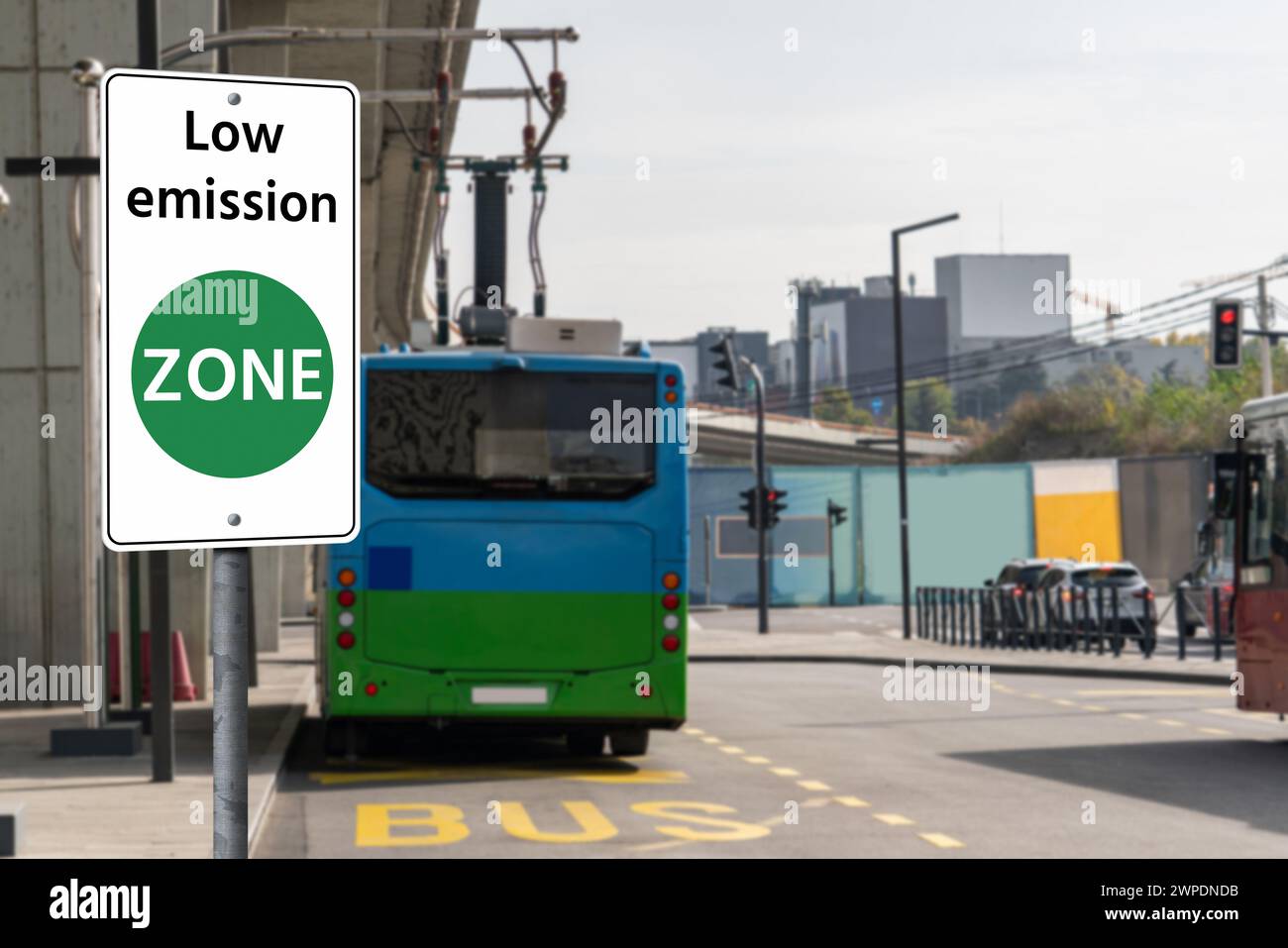 Segnaletica stradale ZONA a basse emissioni su uno sfondo di autobus elettrici verdi. Concetto di mobilità pulita Foto Stock