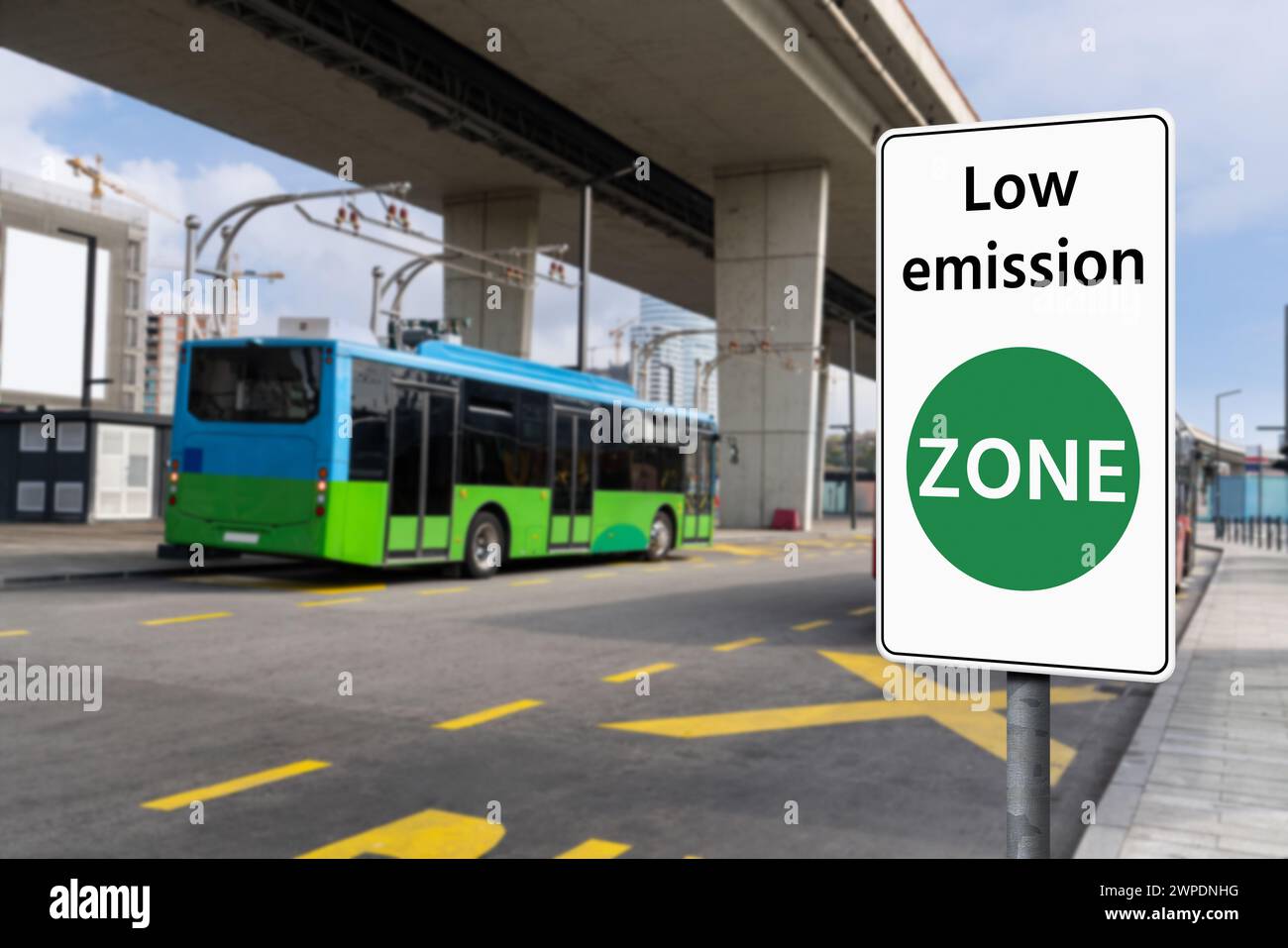 Segnaletica stradale ZONA a basse emissioni su uno sfondo di autobus elettrici verdi. Concetto di mobilità pulita Foto Stock