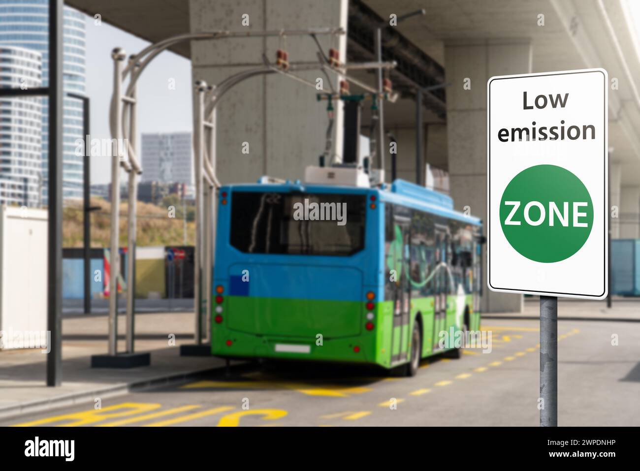 Segnaletica stradale ZONA a basse emissioni su uno sfondo di autobus elettrici verdi. Concetto di mobilità pulita Foto Stock