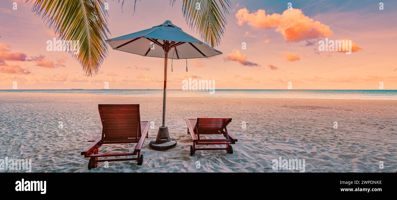 Splendida natura panoramica. Panorama della spiaggia tropicale tramonto esotico paesaggio dell'isola d'estate amore coppia sedie ombrellone foglie di palma costa. Romanticismo Foto Stock