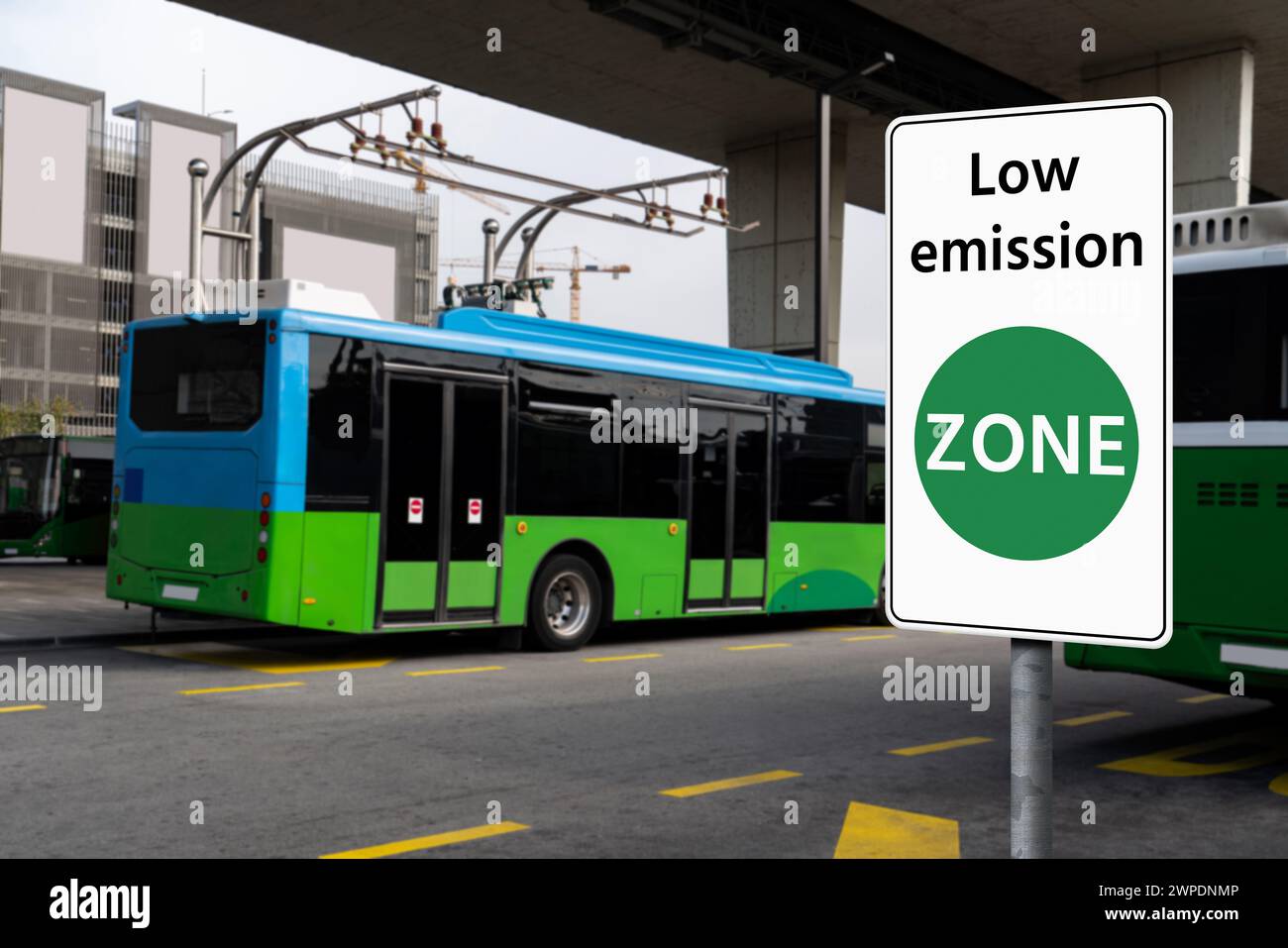 Segnaletica stradale ZONA a basse emissioni su uno sfondo di autobus elettrici verdi. Concetto di mobilità pulita Foto Stock