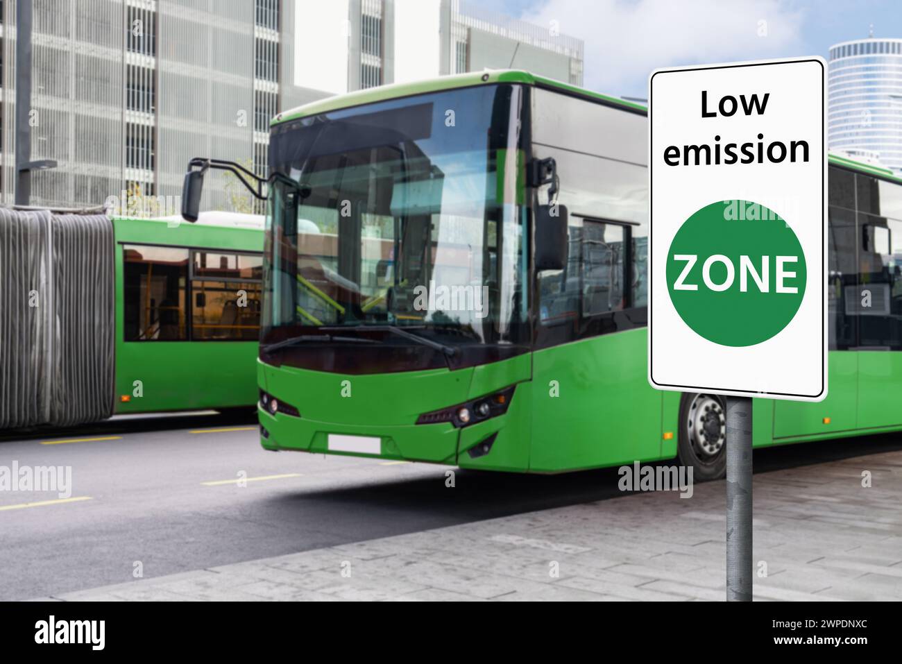 Segnaletica stradale ZONA a basse emissioni su uno sfondo di autobus elettrici verdi. Concetto di mobilità pulita Foto Stock
