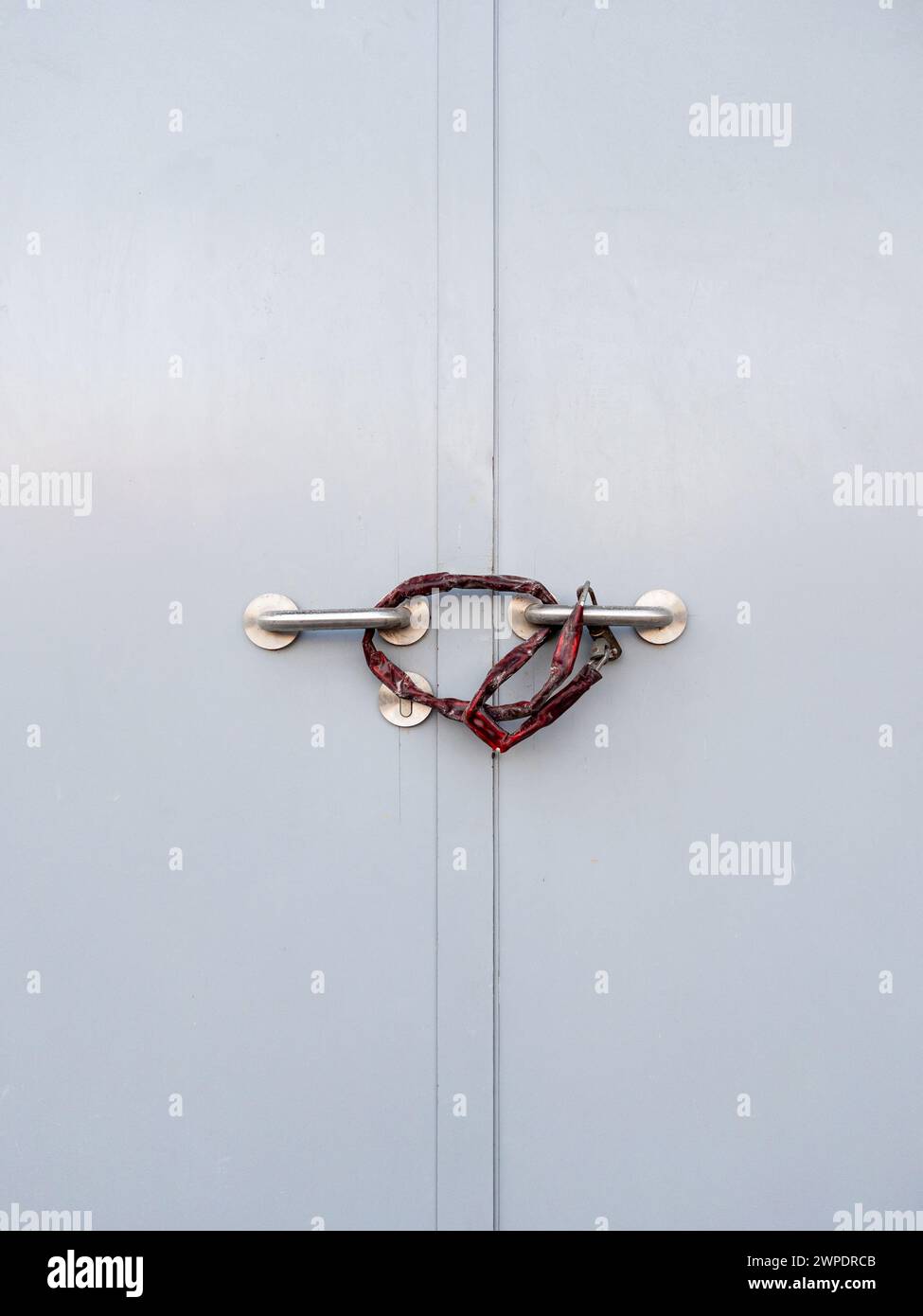 Primo piano della maniglia metallica della porta bloccata con catena e paletta per la sicurezza, sala di controllo elettrica della stazione ferroviaria, vista frontale per il backgroun Foto Stock