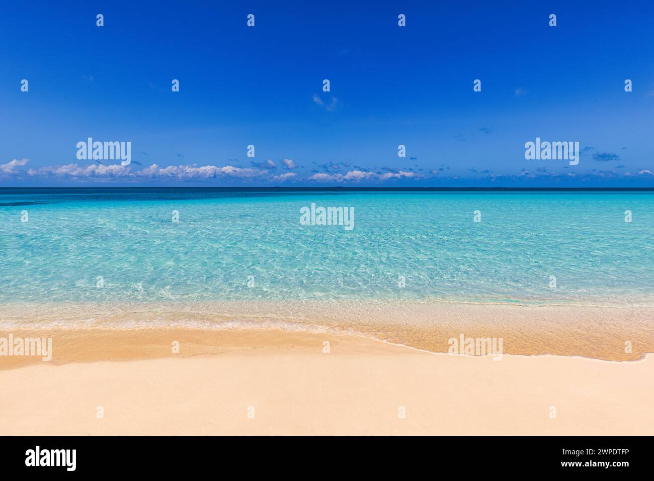 Vista sulla spiaggia tropicale e soleggiata. Sole calmo e rilassante spiaggia vuota, cielo azzurro nuvole felici e sabbia bianca. Tranquillo paesaggio naturale lungo la costa Foto Stock