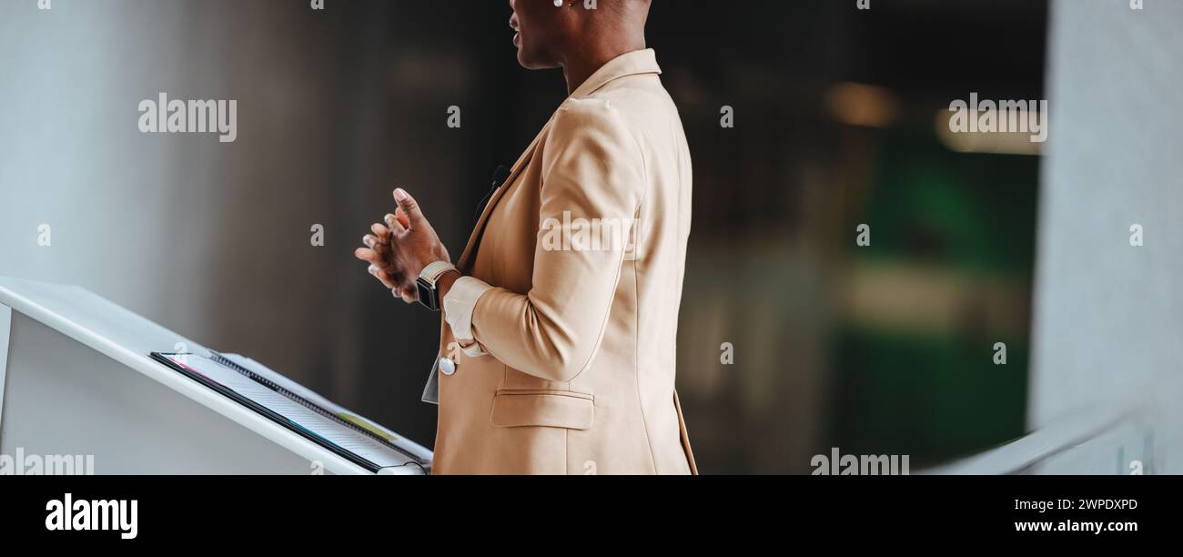 Vista laterale di un professionista pronto a tenere una presentazione durante una conferenza d'affari. Impegnati nel parlare in pubblico, trasudano fiducia e competenza Foto Stock