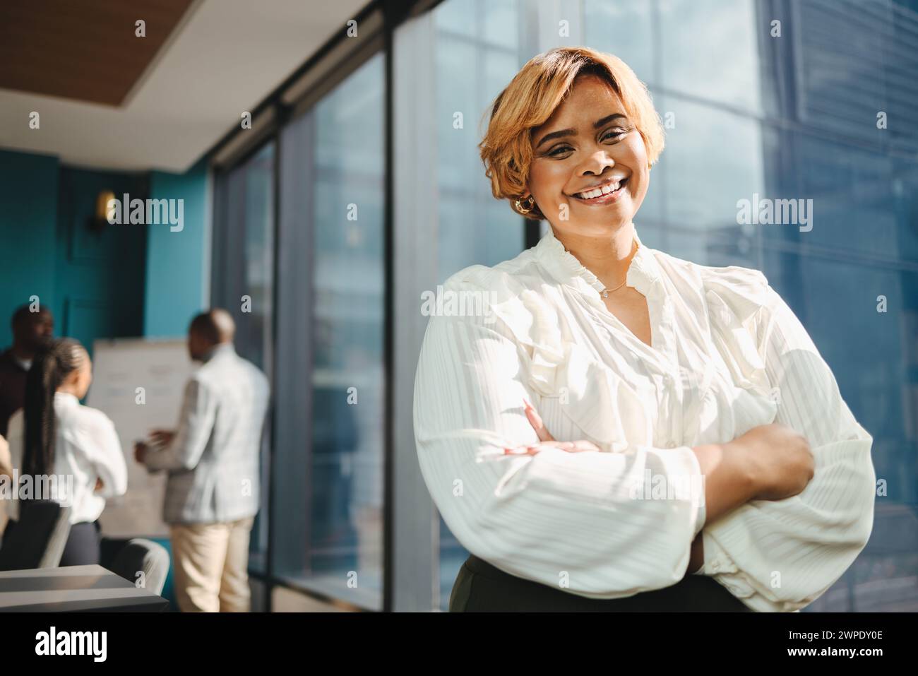Ritratto di una donna d'affari con le braccia incrociate in una sala riunioni di un ufficio. Professionale e felice, si impegna in una riunione di lavoro di successo W Foto Stock
