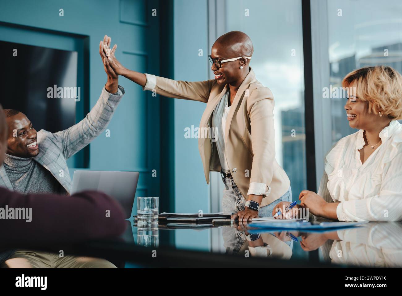 Colleghi professionisti che celebrano il successo in una riunione di lavoro. Uomini e donne in un ufficio aziendale, applaudono felicemente le mani. Dimostrando grande te Foto Stock